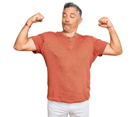 Handsome middle age man wearing casual clothes showing arms muscles smiling proud. fitness concept.