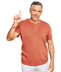Fototapeta premium Handsome middle age man wearing casual clothes showing and pointing up with finger number one while smiling confident and happy.