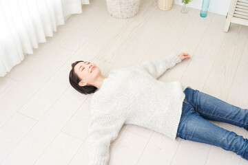 リビングでフローリングに仰向けで寝転ぶ女性
