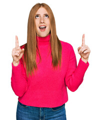 Young irish woman wearing casual clothes amazed and surprised looking up and pointing with fingers and raised arms.