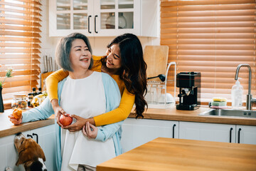 In the kitchen, an old mother receives a loving embrace from her cute young daughter. This...