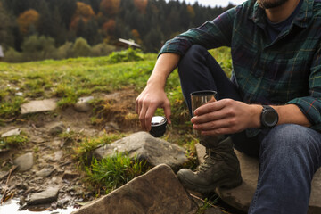 Man with thermo tumbler in nature, closeup. Space for text