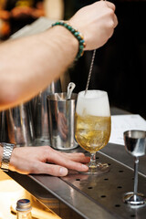 A skilled bartender stirs a cocktail in a tulip glass at a well-equipped bar