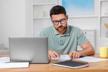 Man calculating taxes at table in room