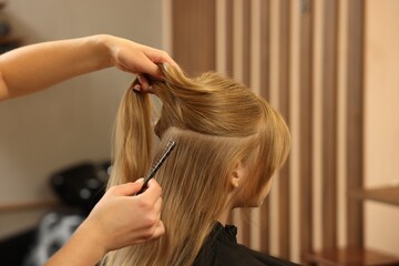 Naklejka premium Professional hairdresser working with girl in beauty salon, closeup