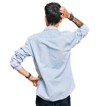 Young hispanic man wearing casual clothes backwards thinking about doubt with hand on head