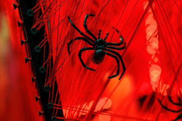 A spooky spider decoration on a web-covered bridge with red lighting.