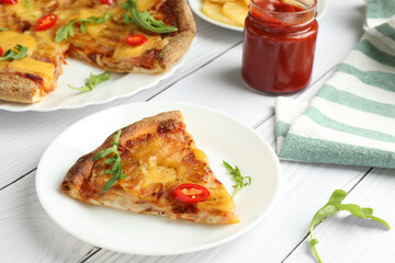 Plate with piece of delicious pineapple pizza on white wooden table