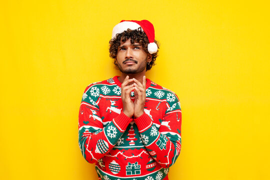 pensive young indian man in new year clothes thinks and plans over yellow isolated background