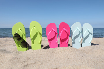 Fototapeta na wymiar Stylish colorful flip flops and sunglasses on beach sand