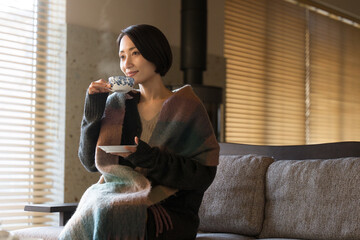 温かい飲み物を飲むストールを羽織った美しい女性  秋冬...