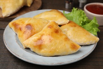 Delicious samosas and lettuce on wooden table, closeup