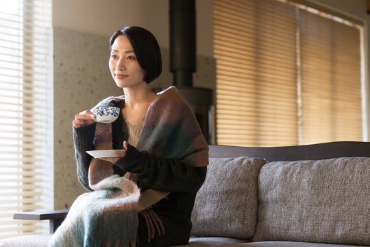 Beautiful Asian (Japanese) woman wearing a stole drinking a hot drink Autumn/Winter