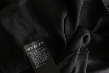 Clothing label in different languages on black garment, closeup