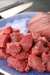 Plate with pieces of raw beef meat on table, closeup