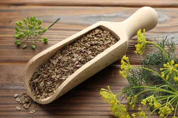 Scoop of dry seeds and fresh dill on wooden table, closeup