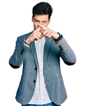 Young hispanic man wearing business clothes rejection expression crossing fingers doing negative sign