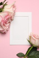 Obraz na płótnie Canvas Empty white frame and beautiful roses on pink background, top view. Space for text