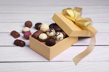 Box with tasty chocolate candies on white wooden table