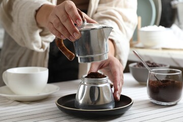 Brewing aromatic coffee. Woman with moka pot at table in kitchen, closeup