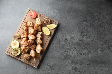 Delicious shish kebabs with vegetables and lemon on grey table, top view. Space for text