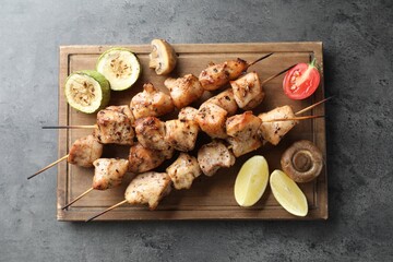 Delicious shish kebabs with vegetables and lemon on grey table, top view
