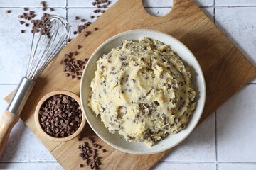 Chocolate chip cookie dough in bowl and metal whisk on table, top view