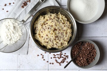 Chocolate chip cookie dough in bowl and ingredients on table, flat lay