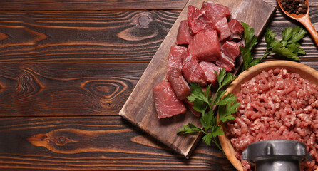 Manual meat grinder, beef, peppercorns and parsley on wooden table, flat lay. Banner design with...