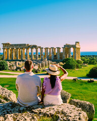 A couple of men and woman visit the Greek temples at Selinunte Sicily during vacation, View the ocean sea and ruins of Greek columns in Selinunte Archaeological historical Park in Sicily Italy