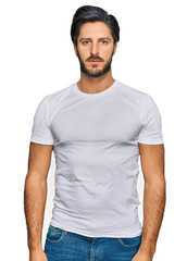 Obraz premium Young hispanic man wearing casual white t shirt relaxed with serious expression on face. simple and natural looking at the camera.
