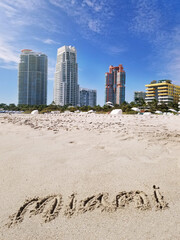 Miami text written in the sand in South Beach with skyline in the distance