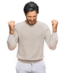 Fototapeta premium Young hispanic man wearing casual clothes very happy and excited doing winner gesture with arms raised, smiling and screaming for success. celebration concept.