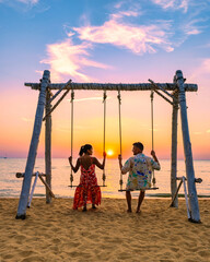 Najomtien Beach Pattaya Thailand, a couple man and a woman mid age watching the sunset on the beach on a swing - obrazy, fototapety, plakaty