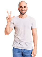 Young handsome man wearing casual t shirt showing and pointing up with fingers number three while smiling confident and happy.