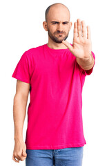 Young handsome man wearing casual t shirt doing stop sing with palm of the hand. warning expression with negative and serious gesture on the face.