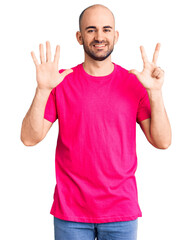 Young handsome man wearing casual t shirt showing and pointing up with fingers number eight while smiling confident and happy.