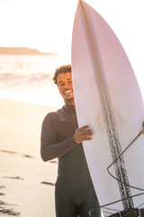 Surfer smiles holding his surfboard.