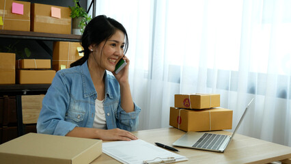 Online seller entrepreneur young asian woman using phone calling, checking online order. Woman...