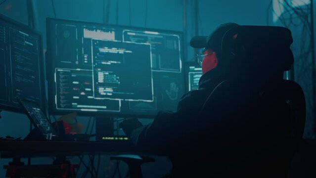 Hacker in cap and glasses coding on computer for cyber crime