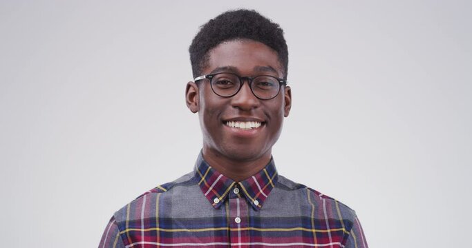 Face, smile and a confident black man in studio on a white background for freedom or expression of emotion. Portrait, relax and a happy young nerd or geek looking natural or carefree in a good mood