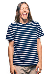 Fototapeta premium Handsome caucasian man with long hair wearing casual striped t-shirt winking looking at the camera with sexy expression, cheerful and happy face.