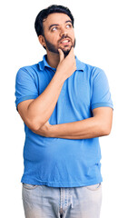 Young hispanic man wearing casual clothes with hand on chin thinking about question, pensive expression. smiling with thoughtful face. doubt concept.