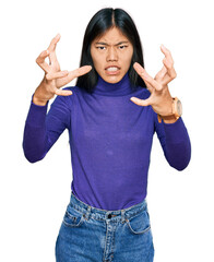 Beautiful young asian woman wearing casual clothes shouting frustrated with rage, hands trying to strangle, yelling mad