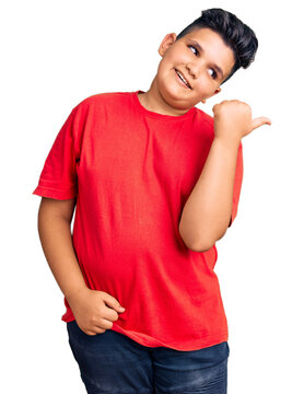 Little boy kid wearing casual clothes smiling with happy face looking and pointing to the side with thumb up.