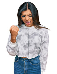 Young latin transsexual transgender woman wearing casual clothes angry and mad raising fist frustrated and furious while shouting with anger. rage and aggressive concept.