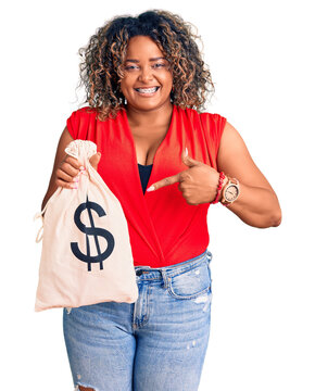 Young african american plus size woman holding money bag with dollar symbol smiling happy pointing with hand and finger