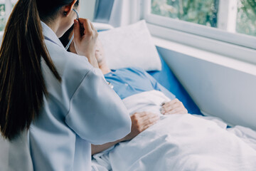 Side view of diverse doctors examining Asian female patient in bed in ward at hospital.
