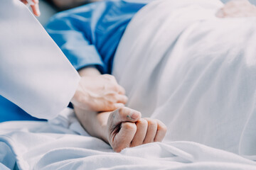 Side view of diverse doctors examining Asian female patient in bed in ward at hospital.