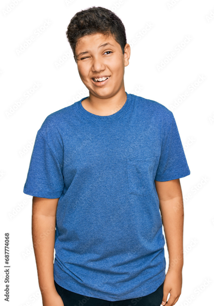 Wall mural Teenager hispanic boy wearing casual clothes winking looking at the camera with sexy expression, cheerful and happy face.